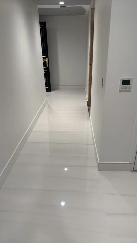 White hallway with a long run of large white tiles with soft grey lines, set flat and straight