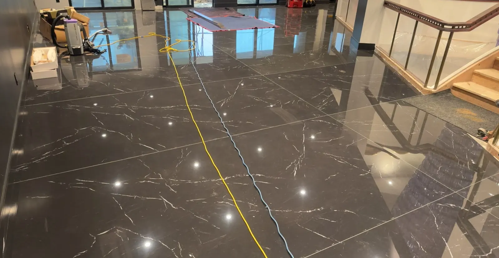 Large dark tile floor during the job, with work lights and cords