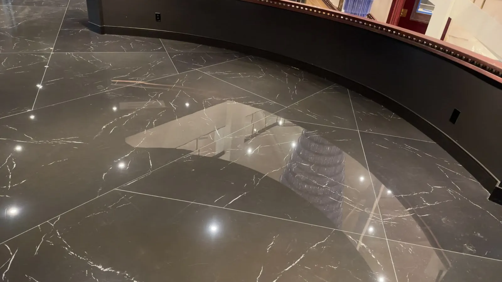 Dark marble-look floor tiles cut to follow the curved edge of a stair opening
