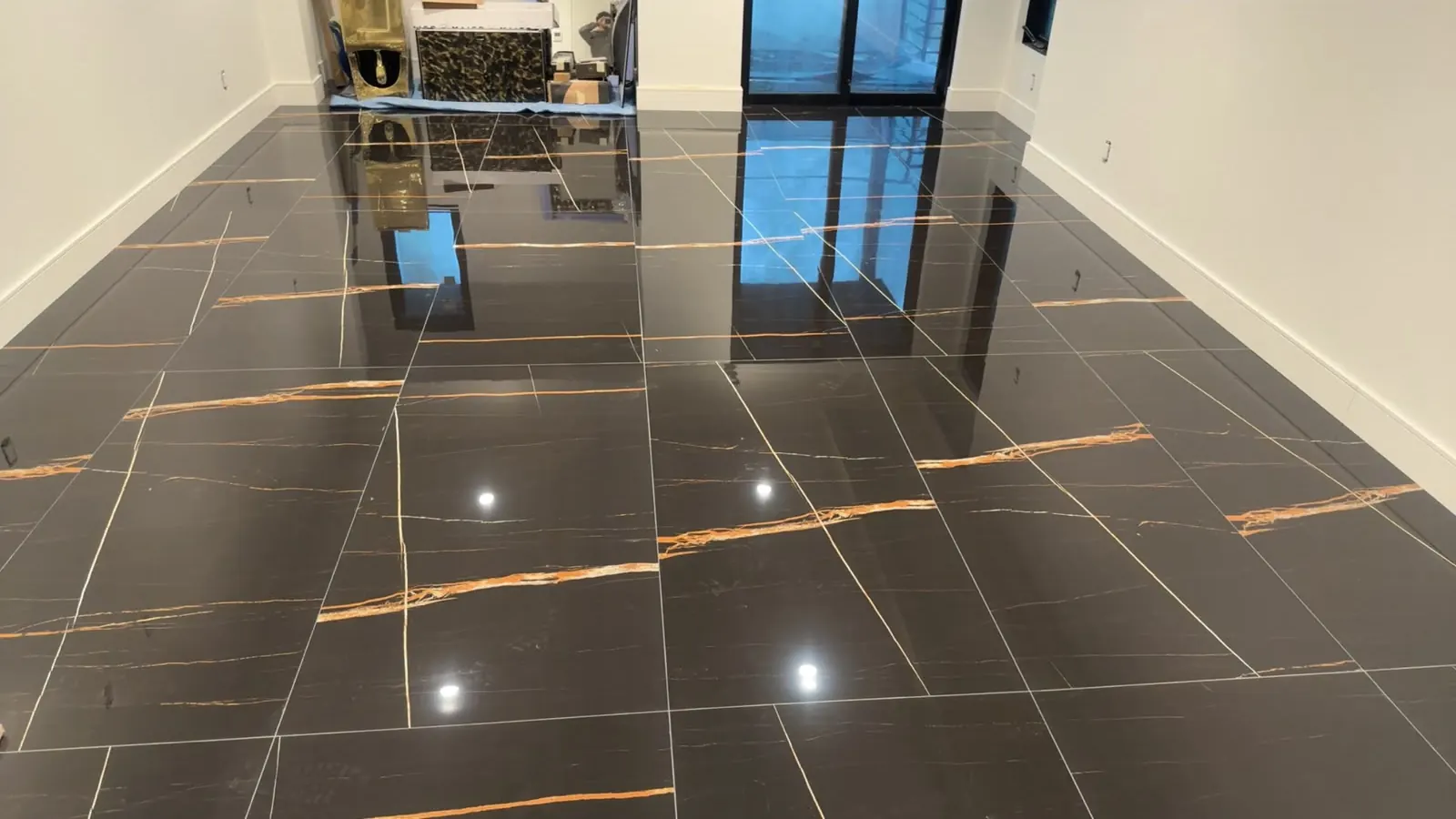 Glossy black tile floor with gold veins running across large square tiles, reflecting the windows