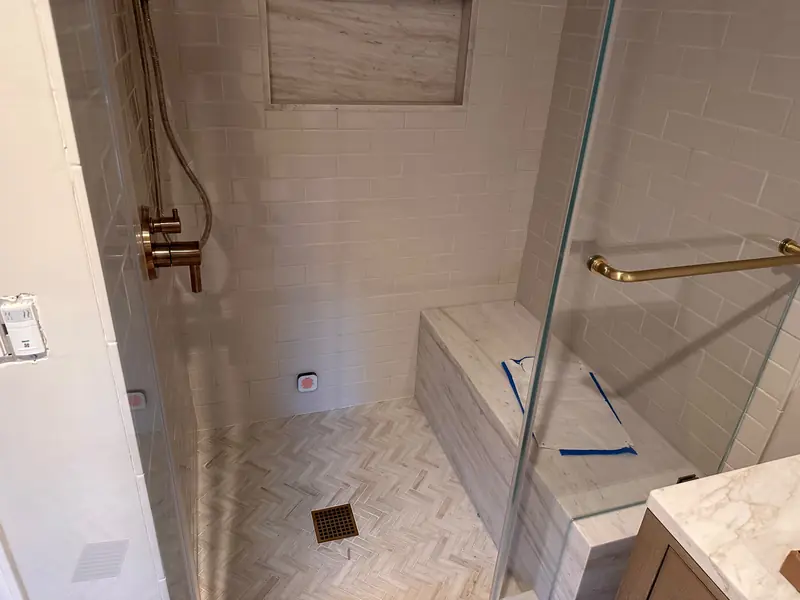 Walk-in shower with white subway tile, a stone bench, a long niche and a herringbone stone floor