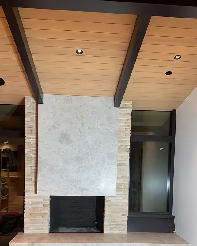 Fireplace with a large light stone panel over the opening, brick-look sides and a long floating stone hearth